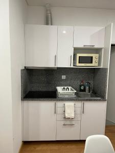 cocina con armarios blancos y microondas en Down Bonjardim Apartments, en Oporto