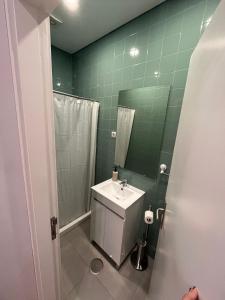 baño verde con lavabo y ducha en Down Bonjardim Apartments, en Oporto