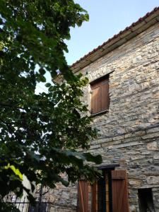 an old stone building with wooden shuttered windows at Aronia Stone House in Lafkos