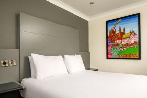 チェスターにあるメルキュール チェスター イースト ホテルの白いベッドと壁に絵画が飾られたベッドルーム1室
