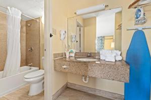 a bathroom with a sink and a toilet and a tub at Developer Inn Downtown Orlando in Orlando