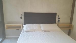 1 dormitorio con 1 cama blanca y 2 estanterías en Terrazas Pinar 3 en Monte Hermoso