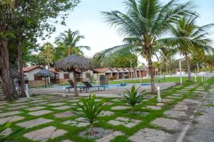 a resort with a swimming pool and palm trees at Orla Nautica in Barreirinhas