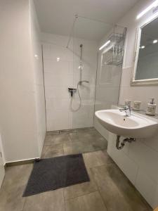 a white bathroom with a sink and a shower at Krimhof in Maasbüll
