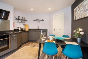 a kitchen with a table and blue chairs at The Holgate Hideaway with Hot Tub in York +10 photos
