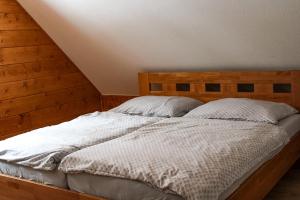a bed with a wooden headboard and two pillows at Chata Holder in Svätý Kríž +12 photos