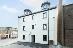 a white building with black windows and a brick wall at South Esk Apartment 8 in Montrose