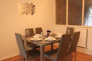 ein Esszimmer mit einem Tisch und Stühlen mit Weingläsern in der Unterkunft Lovely staycation with family FREE Parking & WiFi in Beeston