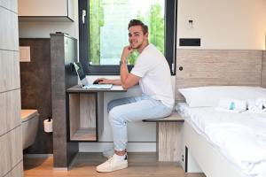 a man sitting at a desk in a bedroom at Roatel Schwabhausen A4 my-roatel-com in Schwabhausen