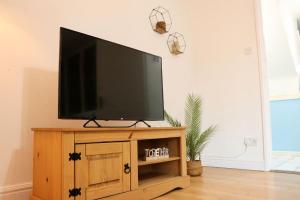a flat screen tv on a wooden stand in a living room at Lovely staycation with family FREE Parking & WiFi in Beeston