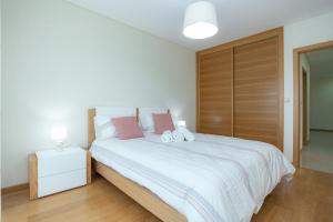 a bedroom with a white bed with a wooden headboard at Buarcos Sunset Apartment by Rent4All in Figueira da Foz