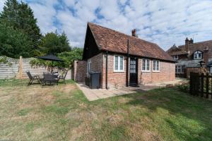 an old brick house with a patio and an umbrella at Cozy One Bedroom Cottage With Spacious Garden +BBQ in Brasted