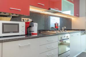 a kitchen with white cabinets and a microwave at Buarcos Sunset Apartment by Rent4All in Figueira da Foz