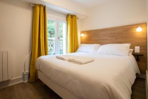 Schlafzimmer mit einem großen weißen Bett und gelben Vorhängen in der Unterkunft Les Arènes Idéal en Famille ou entre Amis in Périgueux