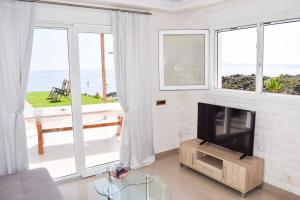 a living room with a television and a view of the ocean at The Three Graces - Artemis in Antimácheia
