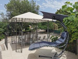 a swing with an umbrella on a patio at Holiday House Rasopasno in Rasopasno