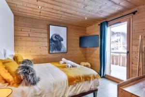 ein Schlafzimmer mit einer Holzwand, einem Bett und einem TV in der Unterkunft Superb and familial duplex in Praz-sur-Arly - Welkeys in Praz-sur-Arly