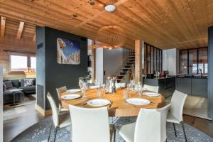 a dining room with a wooden table and white chairs at Duplex Aravis - Welkeys in Praz-sur-Arly