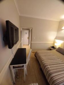 a room with a bed and a desk with a television at Hotel Valles in Mar del Plata