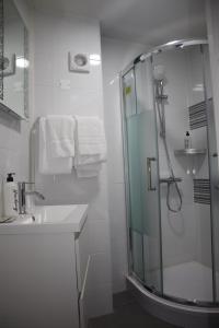 baño blanco con ducha y lavamanos en Le Bellerive, en Peyrat-le-Château