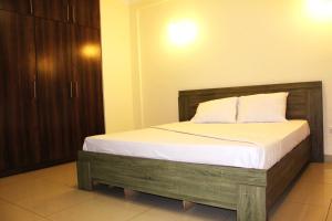 a bedroom with a wooden bed with white sheets at Matola View Residence in Matola