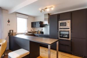 eine Küche mit schwarzen Schränken und einer Arbeitsplatte in der Unterkunft Le ViLoNa - T3 moderne avec parking privé in Rennes