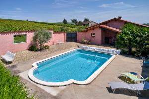 a swimming pool in front of a house at Les Glycines - Domaine Gilles Coperet in Régnié