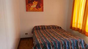 a small bedroom with a bed with a striped comforter at Iquique todo el año in Iquique