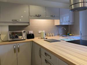 a kitchen with a wooden counter top with a microwave at Lynford Holiday Cottages nestled in the heart of Thetford Forest in Mundford