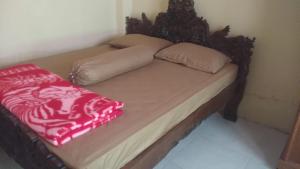 a bed with a wooden headboard and a red blanket on it at HOMESTAY PARAK KAYU in Baso