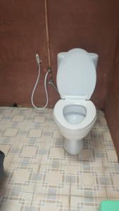 a bathroom with a white toilet with a hose at HOMESTAY PARAK KAYU in Baso