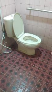 a white toilet in a bathroom with a tile floor at HOMESTAY PARAK KAYU in Baso