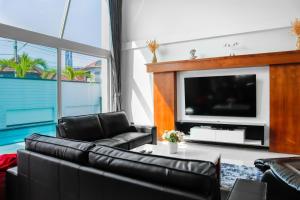 uma sala de estar com mobiliário de couro preto e uma televisão de ecrã plano em *City~house* 芭堤雅豪华泳池别墅近步行街 em South Pattaya