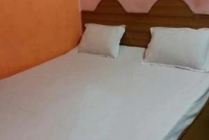 a white bed with two pillows on top of it at Krishna Guest House By WB Inn in Agra