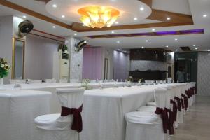 a row of white tables with chairs in a room at Grand Swiss Hotel&Apartment Lahore in Lahore