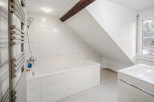un bagno bianco con vasca e lavandino di EH Apartments Jupiter a St. Gallen