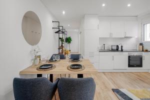 a white kitchen with a wooden table and chairs at EH Apartments Jupiter in St. Gallen