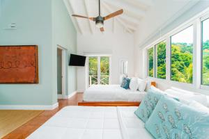 a white bedroom with a bed and a large window at Blue Roatan Resort in West Bay