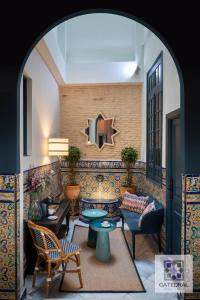una sala de estar con mesas, sillas y una pared en Casa Catedral, en Sevilla