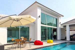 uma casa com uma piscina e um pátio com cadeiras e um guarda-sol em *City~house* 芭堤雅豪华泳池别墅近步行街 em Pattaya Sul