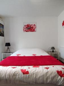 a bedroom with a bed with red flowers on it at Studio Les coquelicots in Saint-Romain-sur-Cher
