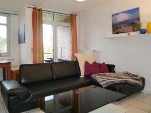 ein Wohnzimmer mit einem schwarzen Ledersofa in der Unterkunft Haus Roland- Whg 23 mit Schwimmbad und Sauna in Zinnowitz