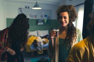 a woman is smiling while holding a glass at Rena's House in Tel Aviv