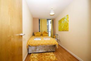 a small bedroom with a bed with a yellow bedspread at Alluring 2 Bedroom Leeds City Centre Apartment- Self Check-in,Balconied Apartment in Leeds