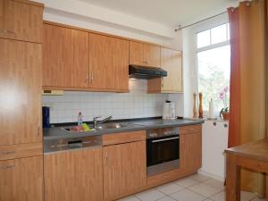 eine Küche mit Holzschränken und Spüle und einem Fenster in der Unterkunft Haus Roland- Whg 23 mit Schwimmbad und Sauna in Zinnowitz