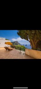 patio con ombrellone, tavolo e panca di VILLA OLGA LUXURY CAPRI a Capri