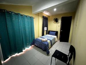 a small bedroom with a bed and blue curtains at Lovely 3-Bed House in Talisay Cebu Philippines in Talisay