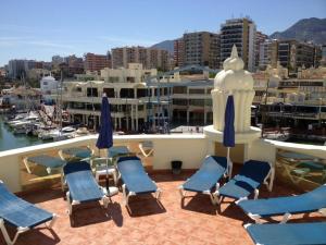eine Gruppe von Stühlen und Sonnenschirmen auf einem Balkon in der Unterkunft Capaldi Luxury Holiday Rentals Puerto Marina Benalmadena in Benalmádena