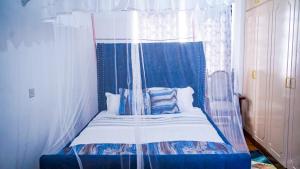 ein Bett mit einem blauen und weißen Baldachin in einem Zimmer in der Unterkunft Primal apartment at Embakasi, Nairobi, Kenya. in Nairobi
