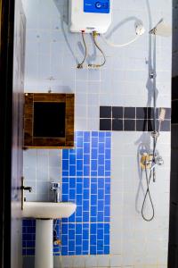 a bathroom with a sink and a shower with blue tiles at Linea Recta 3C in Abuja